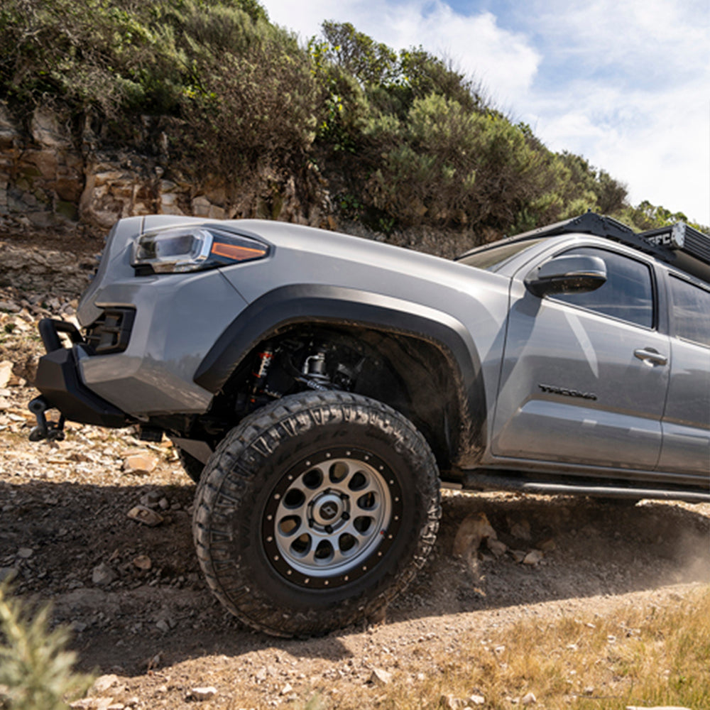 The 2019 Toyota Tacoma is driving down a rocky trail with its FOX Front Factory Race Coil-Over Reservoir Shock 880-06-418 for Toyota Tacoma RWD and 4WD - ADJUSTABLE (Pair), ensuring a long-lasting finish from Fox Racing.