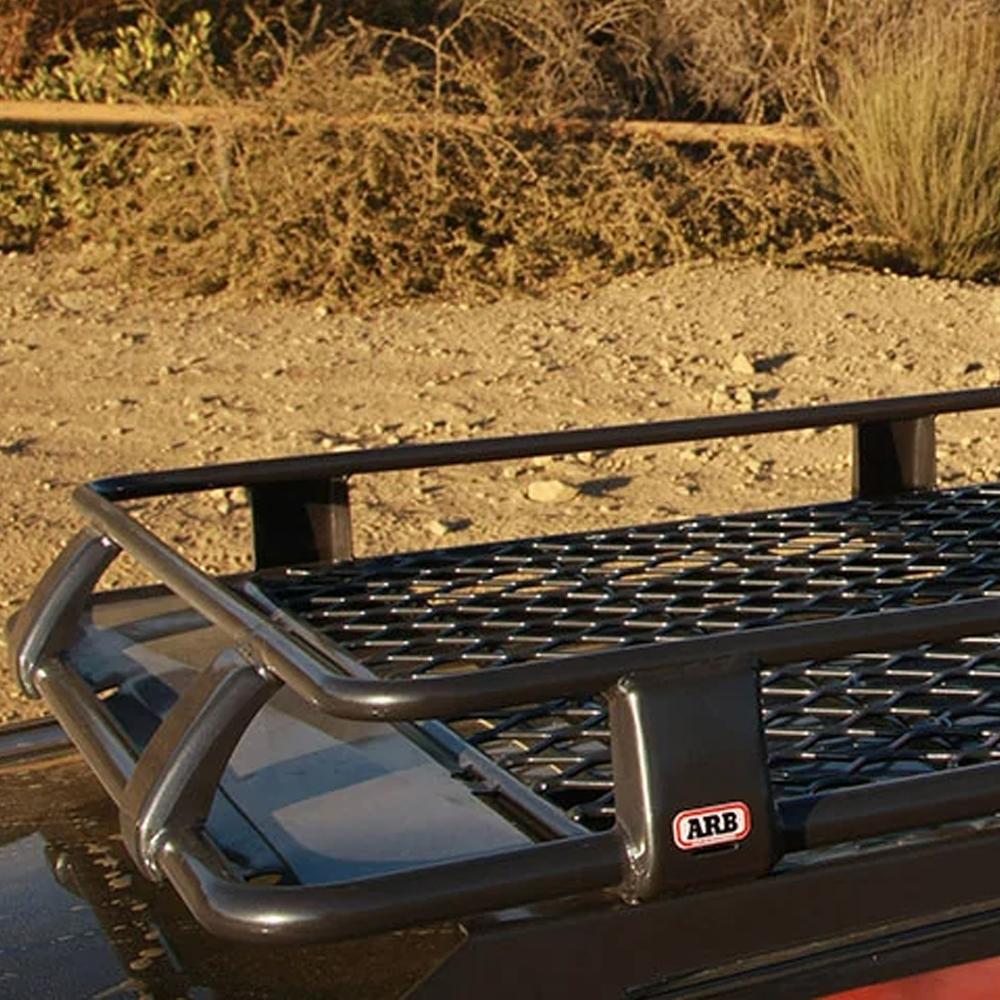 A car with an ARB Alloy Roof Rack Basket 87” X 49” ARB 4900010M on top of it, providing secure storage for belongings while driving.