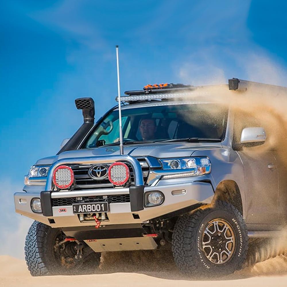 A silver ARB Toyota Land Cruiser with the Alloy Flat Rack 87”X 49” with Mesh Floor ARB 4900060M, driving through the sand.
