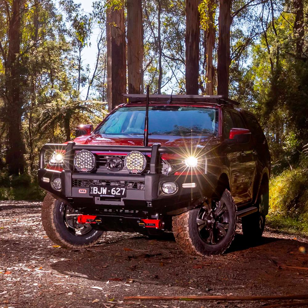 A red ARB Toyota Hilux parked securely in the woods.
