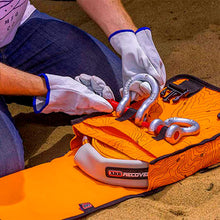 Load image into Gallery viewer, A man is holding a waterproof orange Compact Recovery Bag ARB503A in the sand.