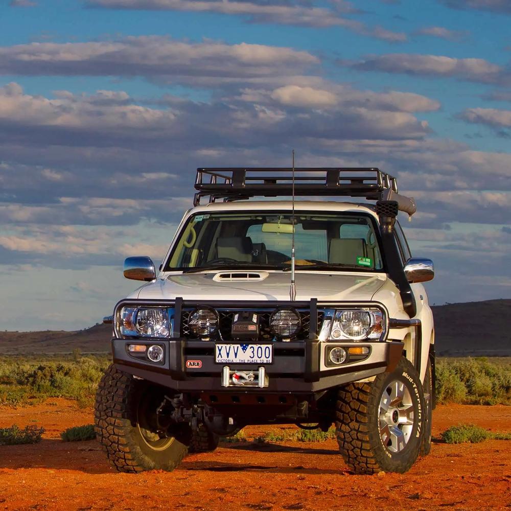 A white truck with a ARB Roof Rack Mounting Kit for NISSAN and Toyota Land Cruiser 3700100 is parked in the desert.