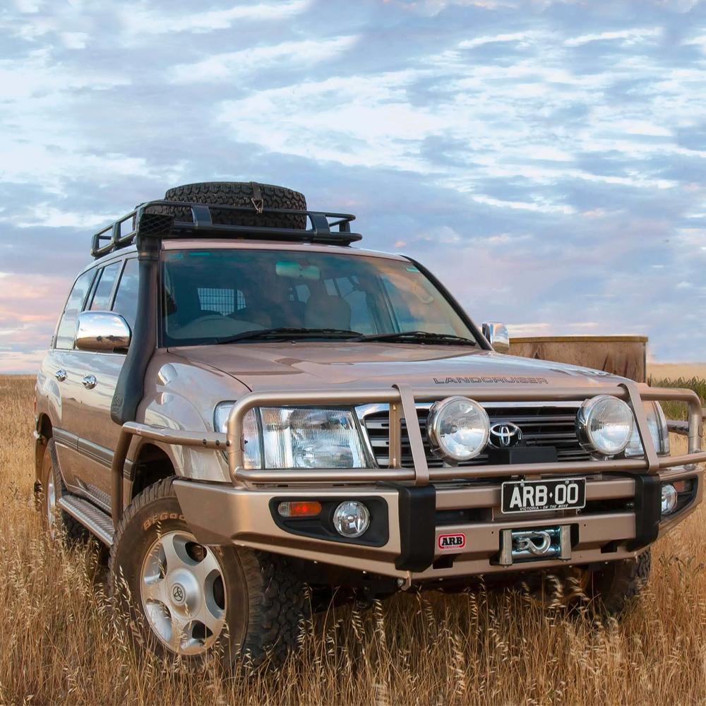 An ARB Roof Rack Fitting Kit 3713010 (87”x49”) for Toyota Landcruiser 100/105 Series and Lexus Lx470 parked in a field, offering secure storage with a high capacity fitting kit.