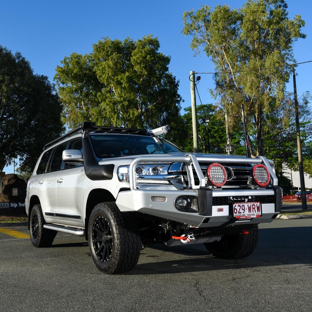 A white ARB Steel Flat Rack 87” X 44” for Toyota Land Cruiser 200 Series 2008 - 2021 parked on a street with secure storage.