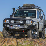 A white Toyota Land Cruiser with an ARB Steel Roof Rack Basket with Mesh Floor (model number 3813020M) is parked on top of a hill, offering secure storage for your belongings.