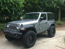 Load image into Gallery viewer, A gray Jeep Wrangler JL 2 Door with larger tires, showcasing the FOX 2 inch Jeep Wrangler JL 2 Door Lift Kit (Standard Load) from Fox Racing, parked on a driveway, showcasing increased load-carrying capacity and enhanced ride quality.