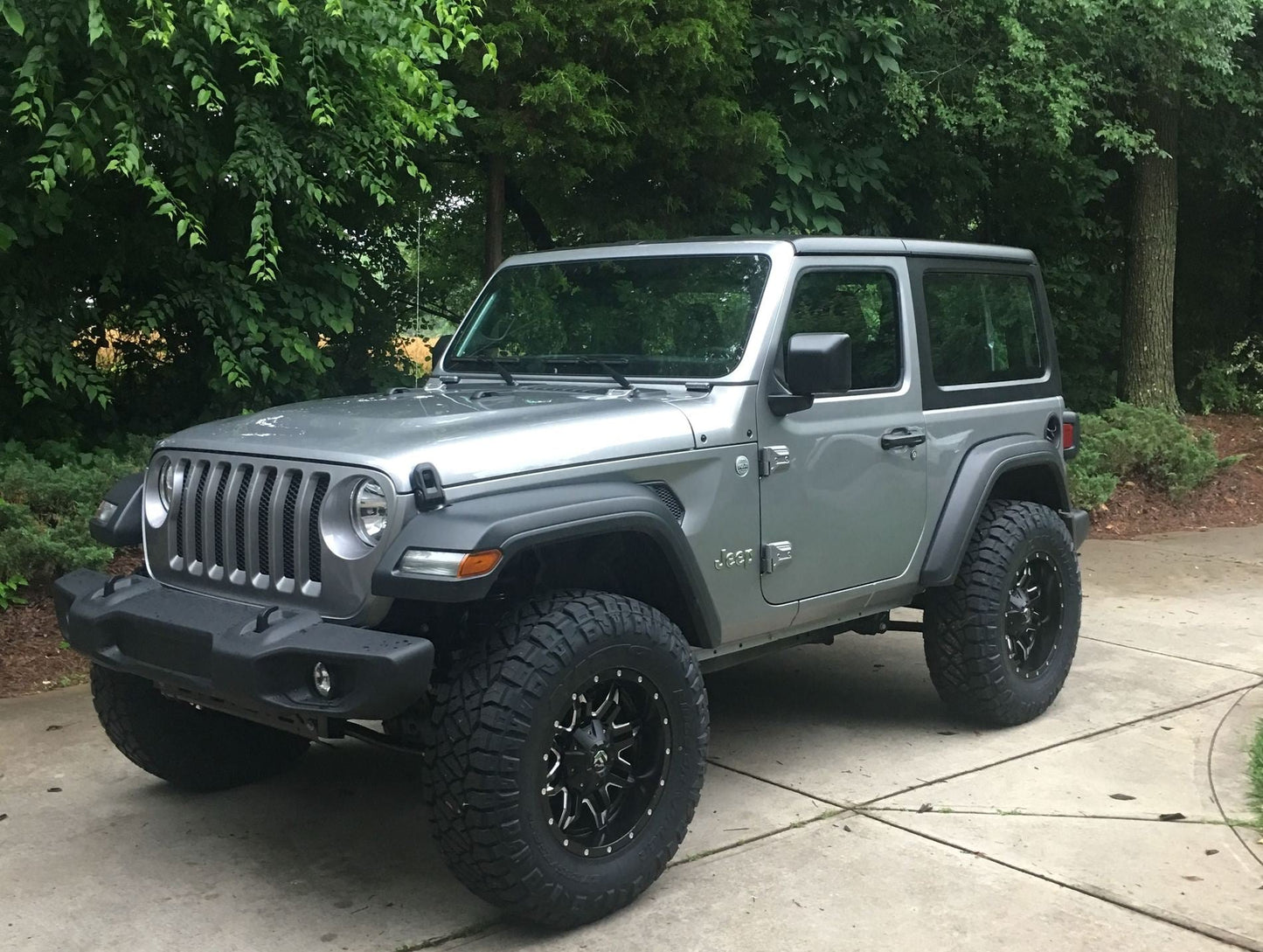 A gray Jeep Wrangler JL 2 Door, fitted with the FOX 2 inch Lift Kit (Medium Load) from Fox Racing, parked on a driveway, showcasing its enhanced ride quality.