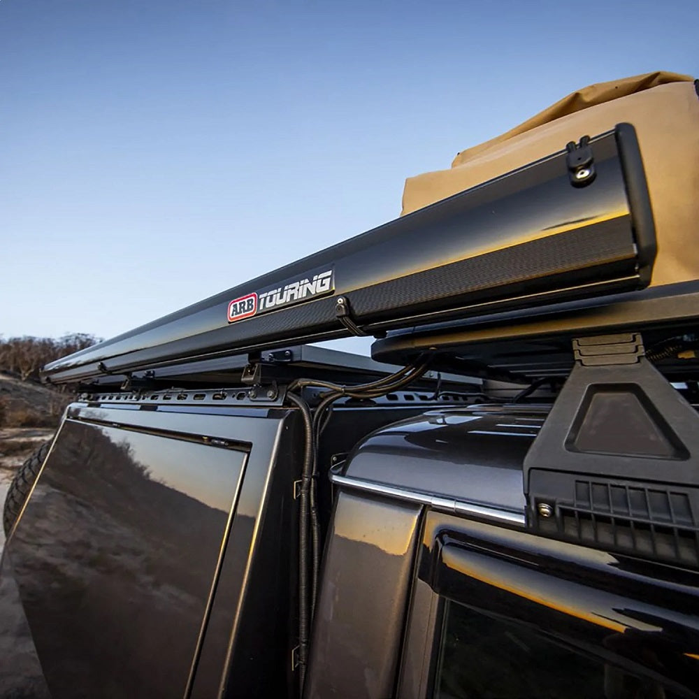 A Black Edition jeep wrangler with an ARB Touring Black Aluminum Awning with Light 814412A on top of it.