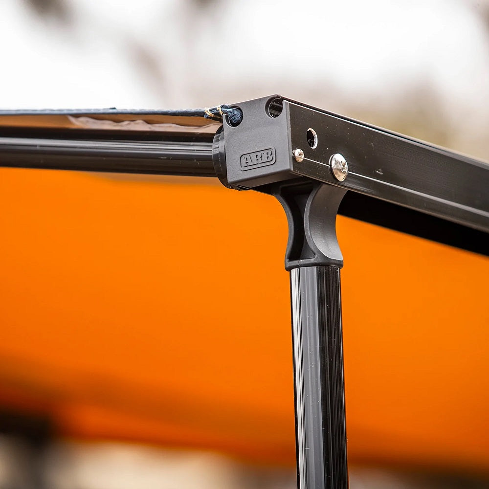 A close up of an orange umbrella with a black frame, featuring the ARB Touring Black Aluminum Awning with Light 814412A.