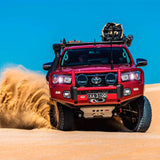 A red Toyota Tacoma with easy installation of Old Man Emu Rear Coil Springs 2896 for Prado150 Series, FJ Cruiser, 4Runner - Constant Load 440 lbs is driving through the sand dunes.