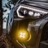 The Morimoto XB LED headlights for Toyota 4Runner (2014-2023) enhance the sleek and stylish appearance of a black SUV. These aftermarket headlights from the Morimoto brand feature yellow lights that not only provide improved visibility but also add a touch of uniqueness to the vehicle.