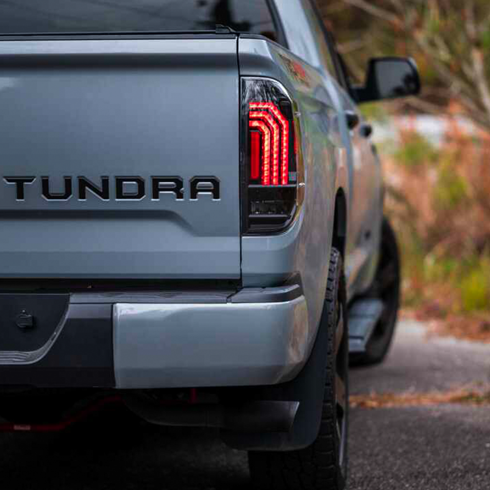 The rear end of a gray pickup truck with Morimoto Xb LED Tails LF705 for Toyota Tundra (2014 - 2021) and a tonnara logo on it.