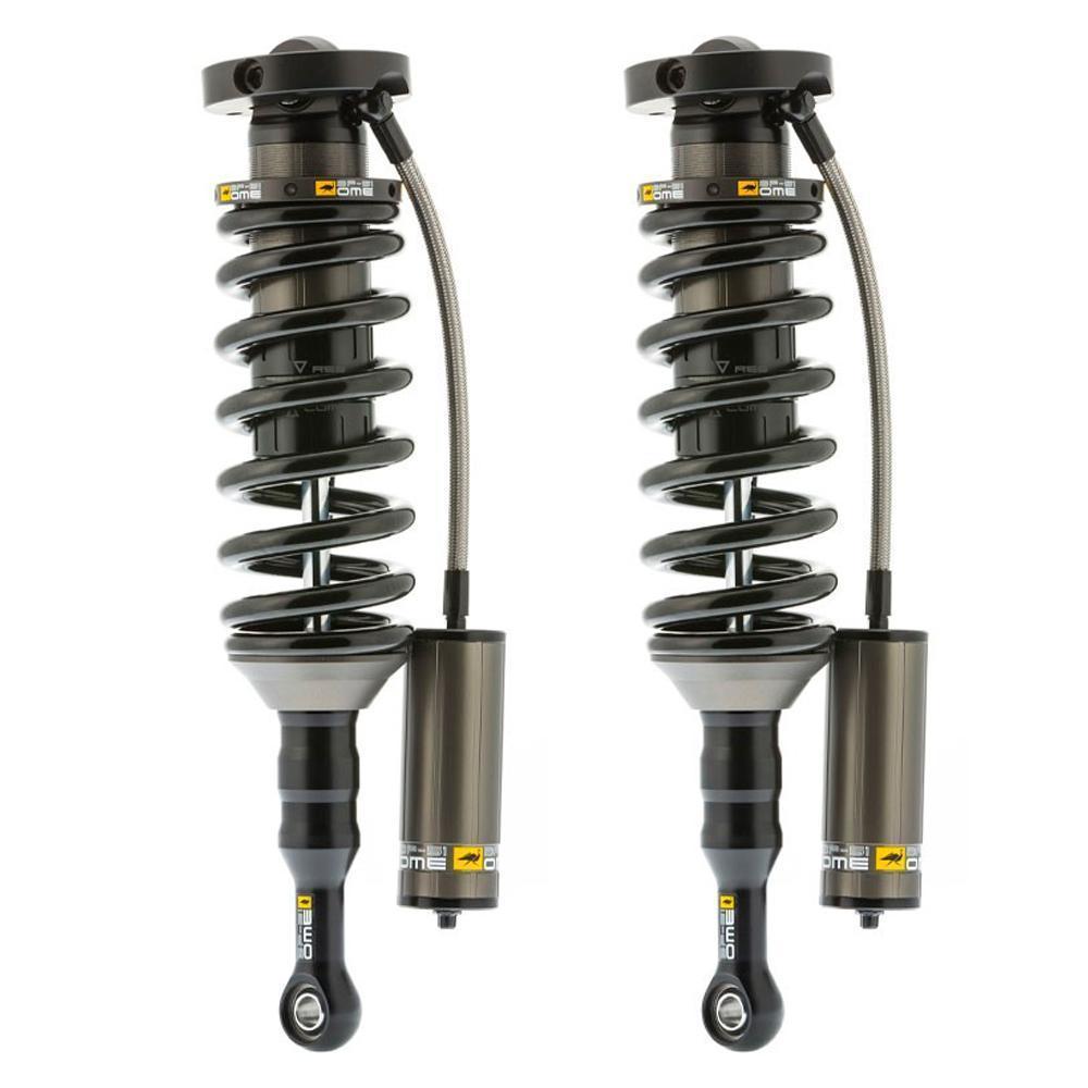 A pair of Old Man Emu shock absorbers for the Toyota Tacoma featuring a remote reservoir and a high-temperature hose.