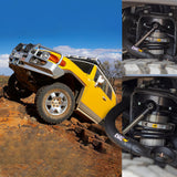 A Toyota FJ Cruiser equipped with an Old Man Emu BP-51 2.5 - 3 inch Lift Kit for FJ Cruiser (10-ON) suspension and shock absorbers, driving on a dirt road.