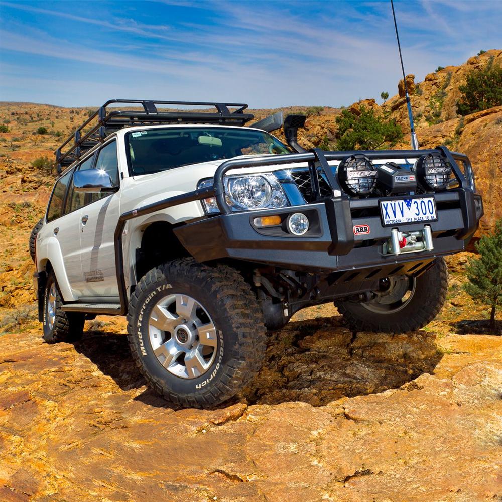 An ARB Roof Rack Mounting Kit for NISSAN and Toyota Land Cruiser ARB 3700100 is parked on a rocky area.