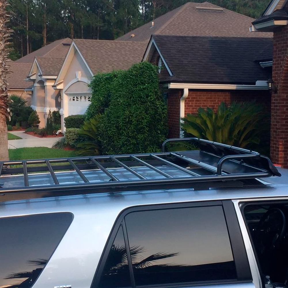 An ARB Touring Roof Rack FJ Cruiser (2007-2009) 3800200KLC2, equipped with a roof rack, is parked in front of a house.