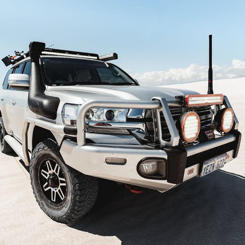 The ARB Steel Flat Rack 87” X 44” for Toyota Land Cruiser 200 Series 2008 - 2021, equipped with a high capacity fitting kit, is parked in the desert providing secure storage capabilities.