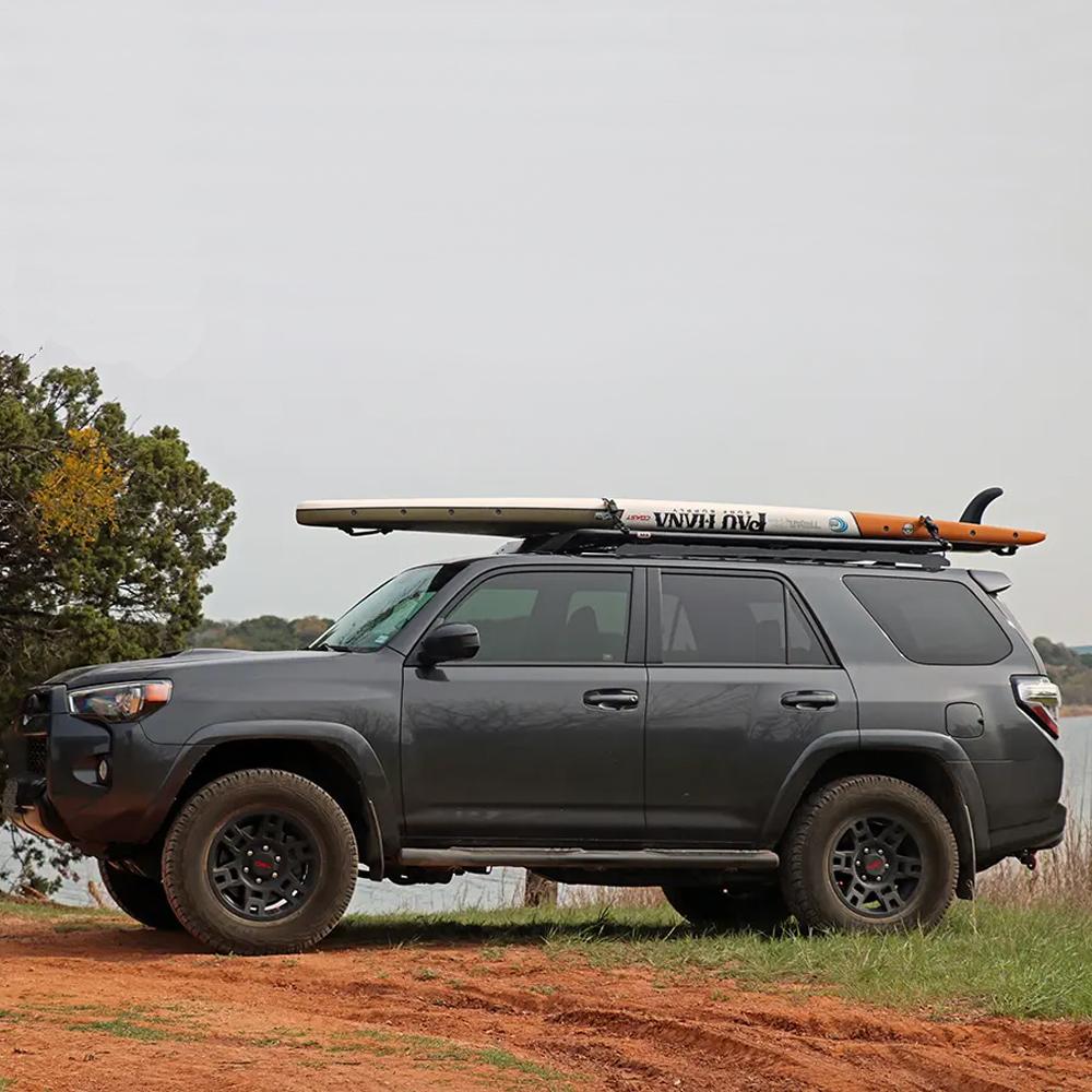 An ARB Steel Flat Rack 70” X 44” for Toyota 4Runner 2003-2009 equipped with roof racks carrying a surfboard on top.