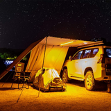 A waterproof SUV is parked under an ARB Touring Awning with Light 814409 at night.