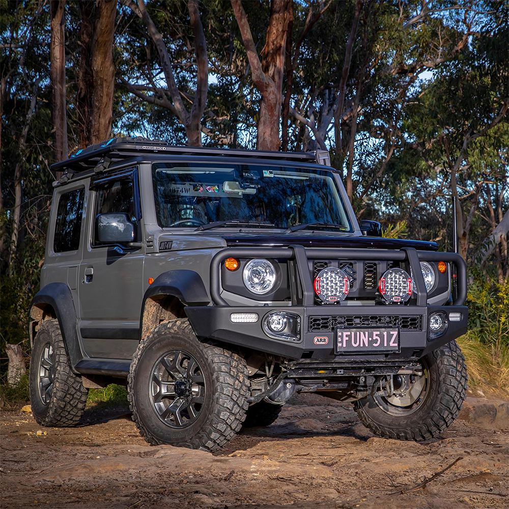 A gray ARB jeep with a virtually unbreakable polycarbonate lens is parked on a dirt road.