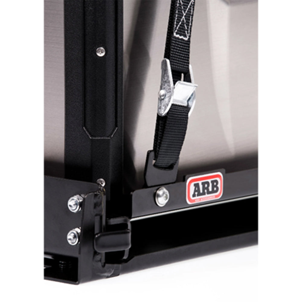 An ARB Portable Fridge Freezer Tie Down Kit Use w/Elements 63QT 10900038, designed as a tie-down system to prevent damage, is a black box with a strap attached to it.