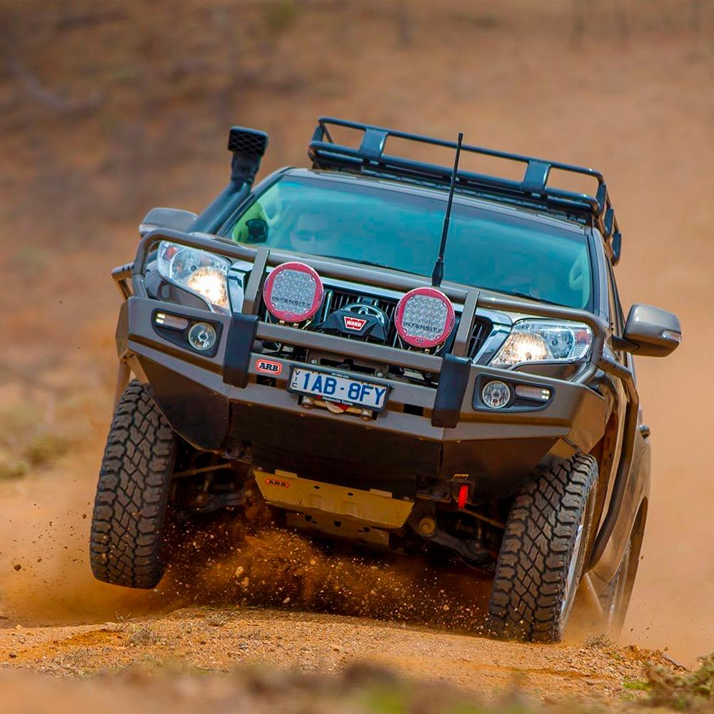 An Old Man Emu lifted off-road vehicle navigating through a dirt road with ARB Old Man Emu Front Coil Springs 2885 for Toyota Prado 150 & 120 Series, FJ Cruiser, Hilux, 4Runner upgraded springs.