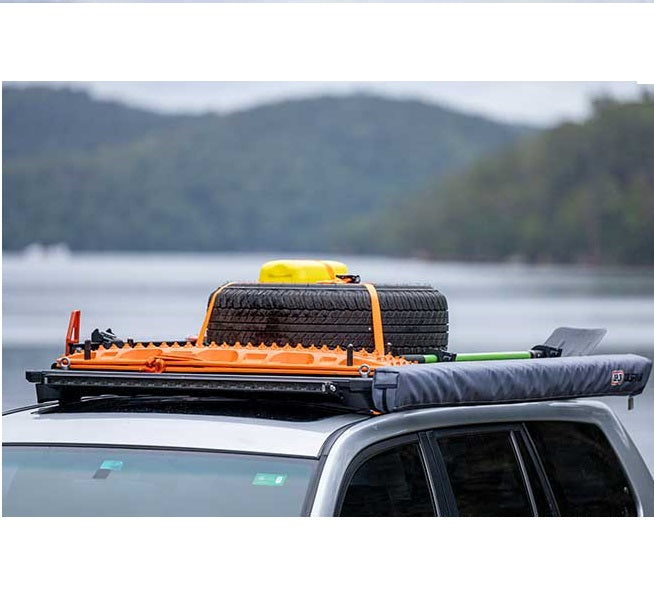 A car equipped with an ARB Rack featuring ARB Eye Bolt Tie-Downs (Set Of Four) 1780200, designed to secure a surfboard on top using the innovative dovetail system.