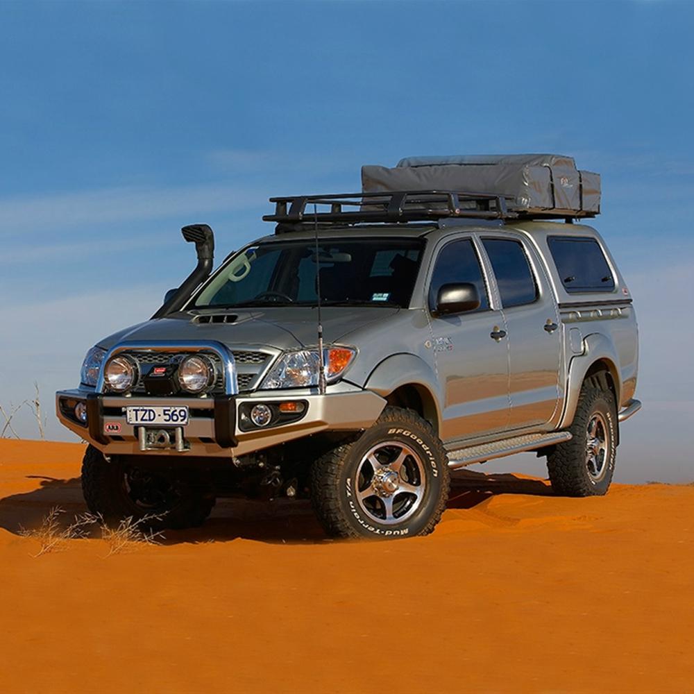 A silver ARB Toyota Hilux with secure storage is parked in the desert.