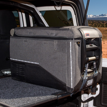 Load image into Gallery viewer, An ARB Protective Cover Transit Bag Canvas for 50 Quarts ARB Fridge Freezers 10900013 to protect the fridge in the back of a jeep.