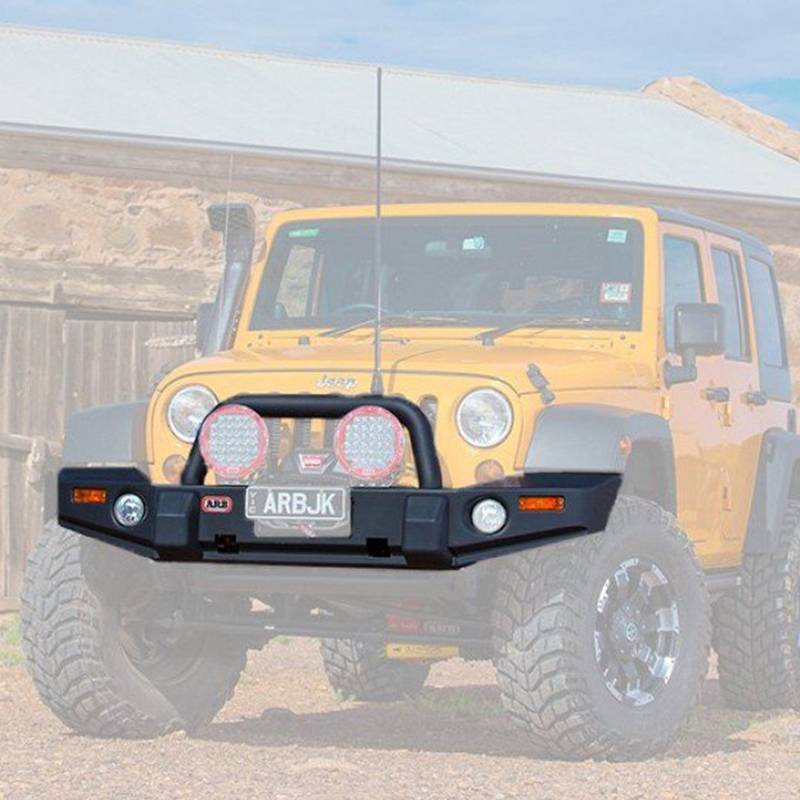 A yellow ARB Deluxe Bumper Combo Bar For Jeep Wrangler JK 2007-2023 ARB 3450240 with vehicle integration is parked in front of a barn.