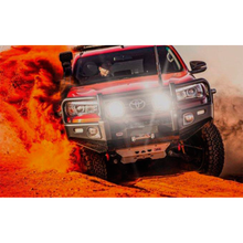 Load image into Gallery viewer, A red Toyota Tacoma with an ARB Intensity Solis Lighting Kit + Wiring Loom (SPOT/SPOT) SJB36S / SJBHARN driving through the desert.