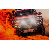 A red ARB Intensity Solis Lighting Kit + Wiring Loom (FLOOD/FLOOD) SJB36F / SJBHARN Toyota Tacoma driving through the dusty and waterproof desert.