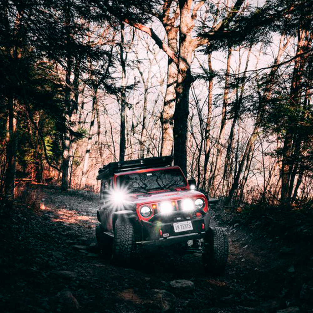 A waterproof red ARB jeep driving through the intense woods.