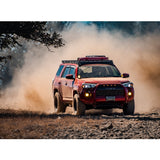 A red Toyota 4Runner with exceptional off-road performance is driving down a dirt road, thanks to its advanced damping characteristics and equipped with cutting-edge King Shocks. It is also fitted with the KING 0 - 2 inch Leveling Kit for 4Runner (10-23) from King Shocks.