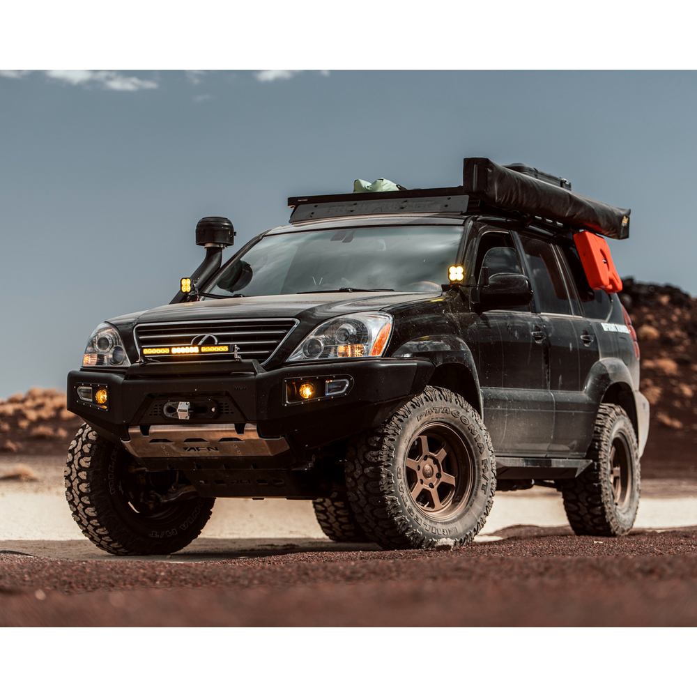 A black Lexus GX470 (03-09) with enhanced off-road performance is parked in the desert, showcasing its impressive suspension articulation and equipped with King Shocks.