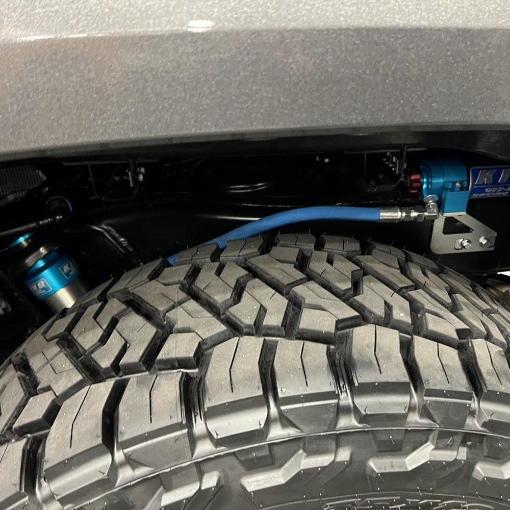 A King Shocks Lift Kit for LandCruiser 200 Series (08-21) with a blue hose attached to it, showcasing its off-road performance.