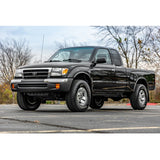 A black Toyota Tacoma with a King Shocks 2 - 2.5 inch Lift Kit for Tacoma (98-04) is parked in a parking lot.