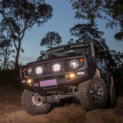 A refined ARB Intensity Solis 21 Flood Driving Light SJB21F-equipped Nissan FJ Cruiser conquering a wet and muddy dirt road at night, showcasing its waterproof capabilities.