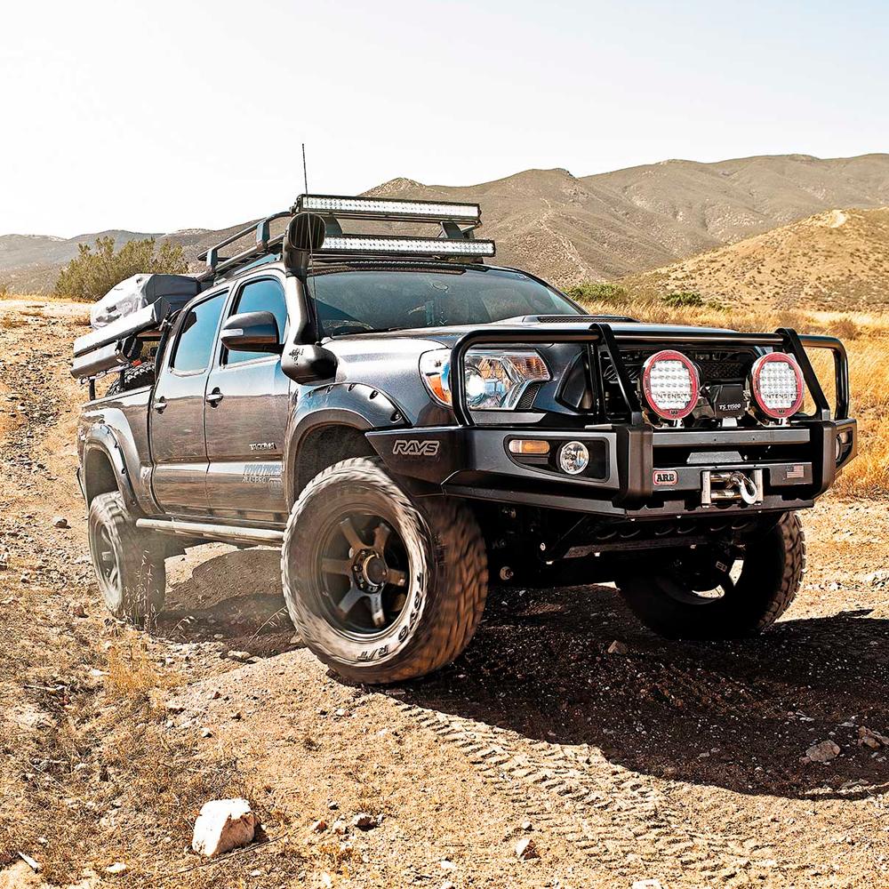 An Old Man Emu Toyota Tacoma equipped with compression valving is driving down a dirt road.