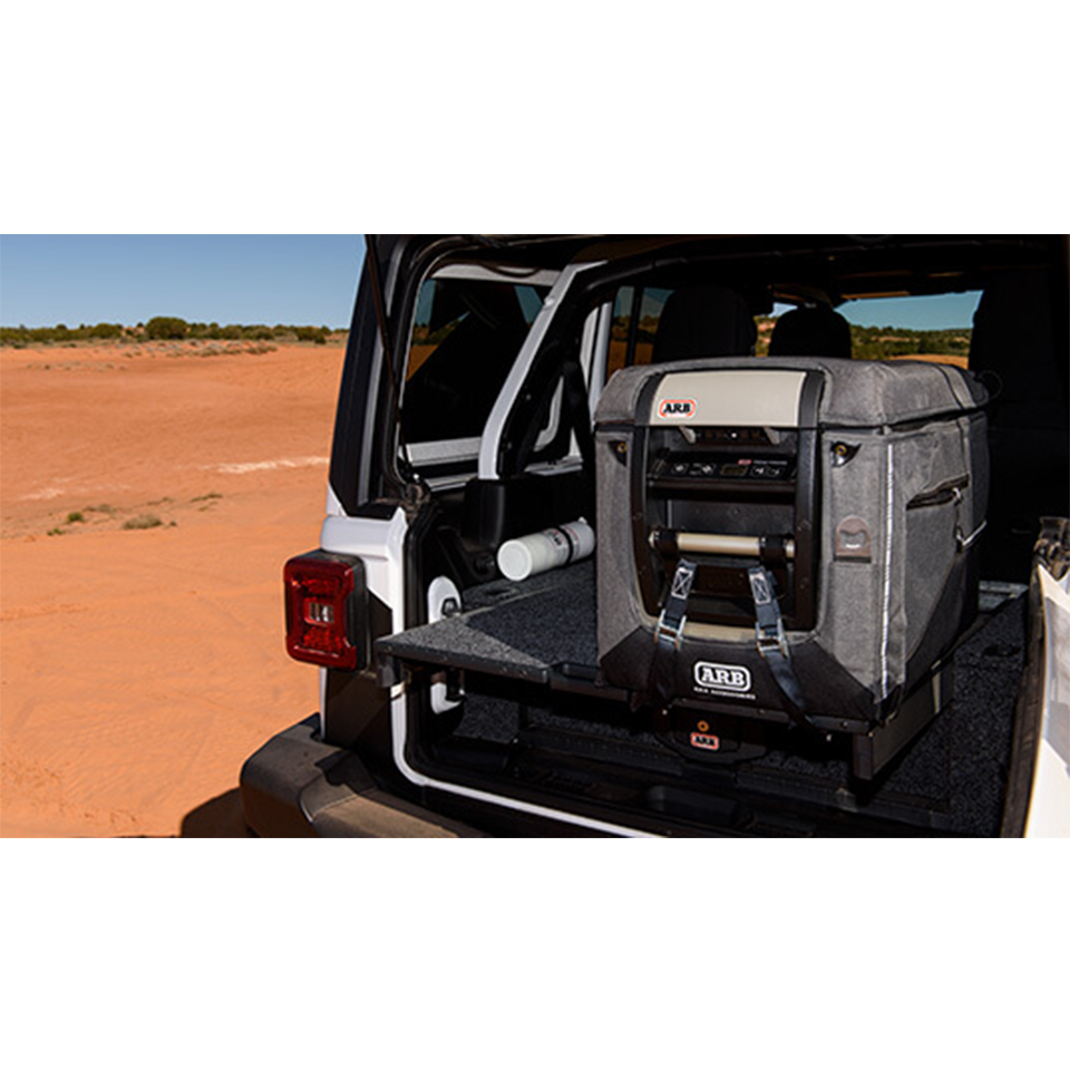 The back of a jeep with an ARB Classic Series II 63 Quarts Portable Fridge Freezer Electric Powered 12V/110V 10801602 cooler in it, featuring gun-metal color accent and equipped with Bluetooth connectivity controlled via a mobile application.