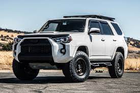 The white 2019 ARB Toyota 4Runner is parked on a dirt road, showcasing its steel build and excellent visibility.