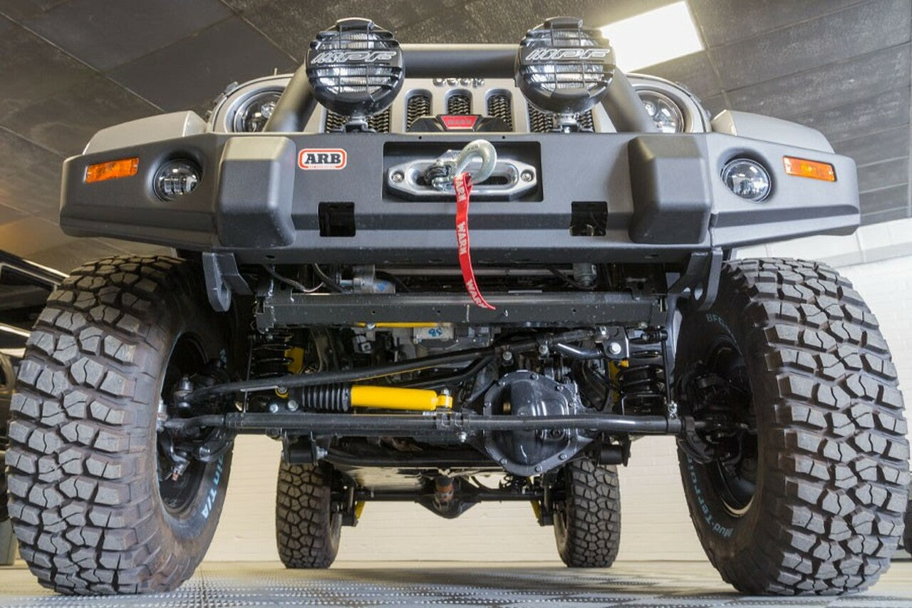 The front end of a jeep wrangler in a garage featuring the installation of Old Man Emu 4WD suspension and Old Man Emu Steering Stabilizer OMESD48.