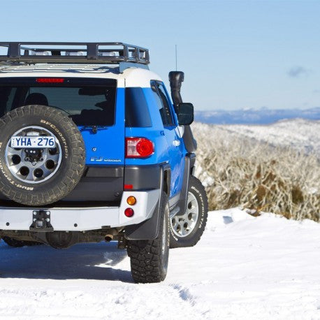 A blue Toyota FJ Cruiser with an ARB Rear Bumper for Toyota FJ Cruiser 2010-2016 ARB 5620020 is parked in the snow.