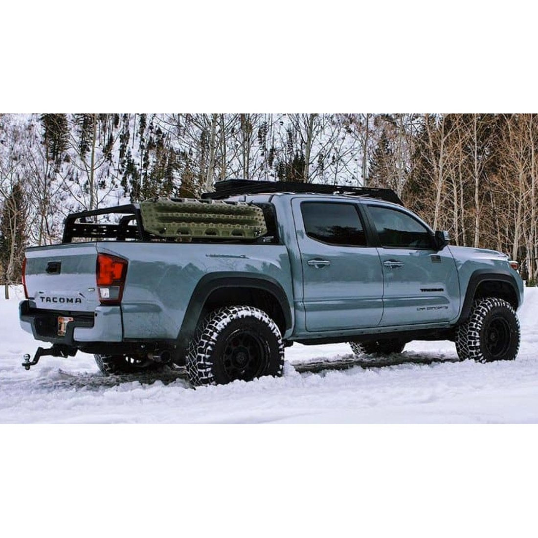 A Toyota Tacoma equipped with an Old Man Emu OME BP-51 2-3 inch Lift Kit for Tacoma (05-23) bravely maneuvers through the snowy terrain with its adjustable damping capabilities.