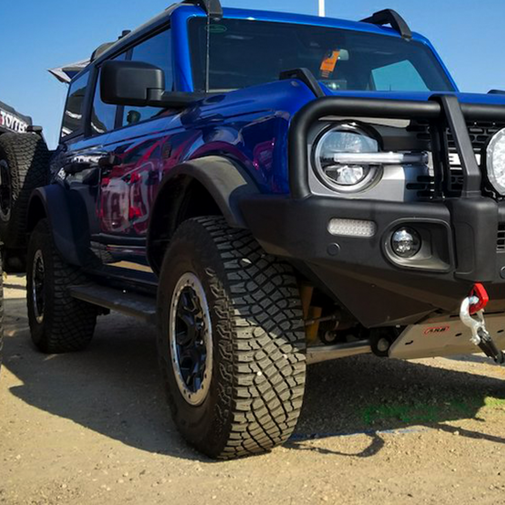 A blue Ford Bronco is parked in a dirt lot, showcasing its ride quality and showcasing the performance of the ARB Old Man Emu Front Stabilizer Bar Kit OMESTAB10 for Ford Bronco.