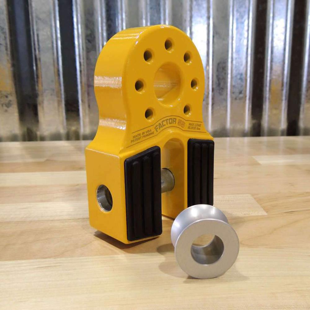 A pair of yellow Factor 55 clamps securely fasten a Factor 55 Synthetic Rope Spool 00096 onto a wooden table, providing corrosion protection for the load spool.