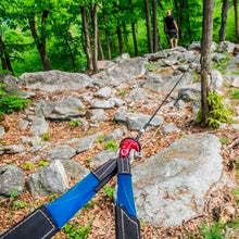 Load image into Gallery viewer, A person is using a Factor 55 Shackle Mount in Red 00015-01 to hold a rope on a rock in the woods.