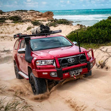 Load image into Gallery viewer, An Old Man Emu red Toyota Tacoma with ARB Old Man Emu Rear Coil Springs 2896 for Prado150 Series, FJ Cruiser, 4Runner - Constant Load 440 lbs. is driving through the sand on the beach, showcasing its ride height and easy installation.