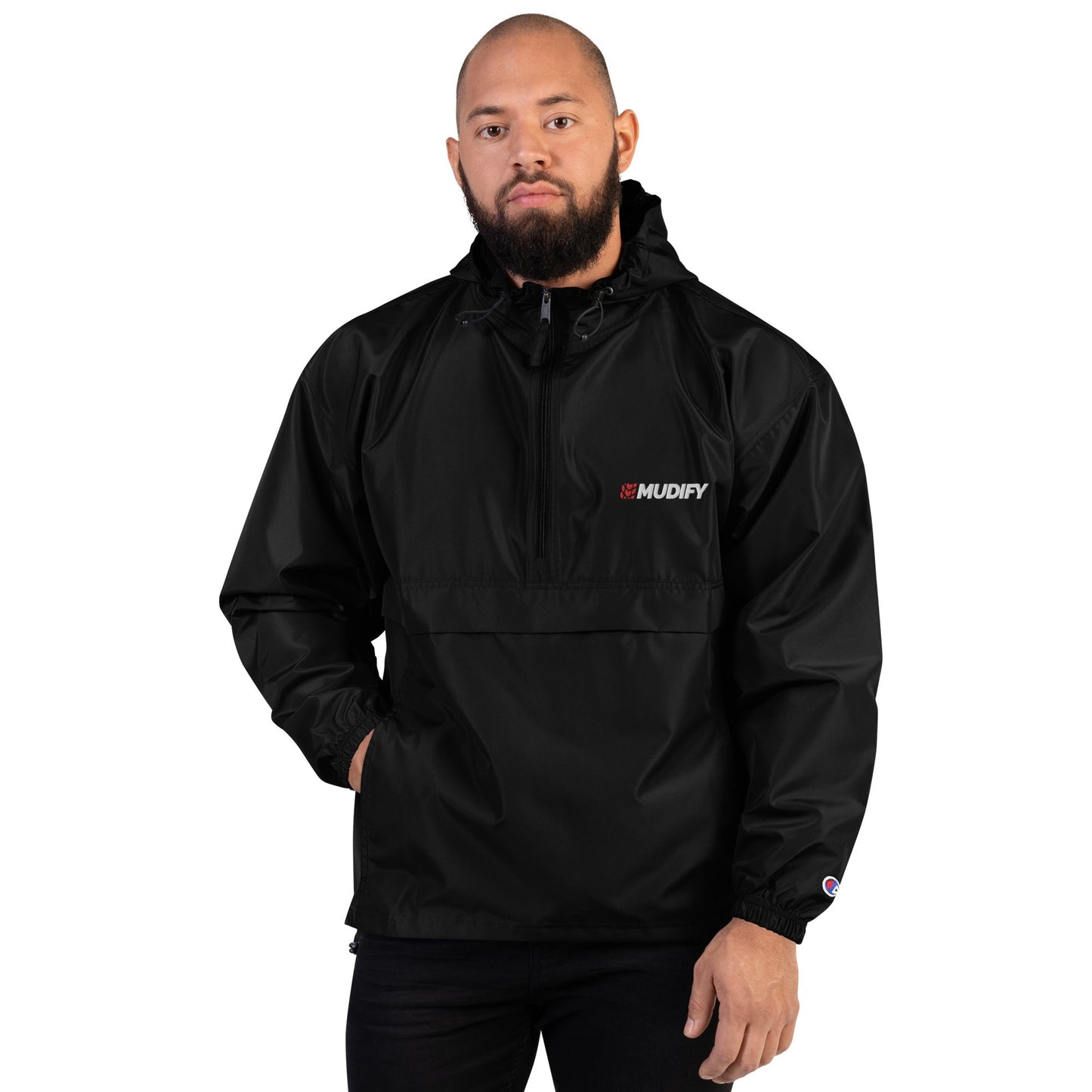 A man wearing a Mudify Embroidered Packable Jacket, which is wind and rain resistant with a black hood and the word Champion on it.