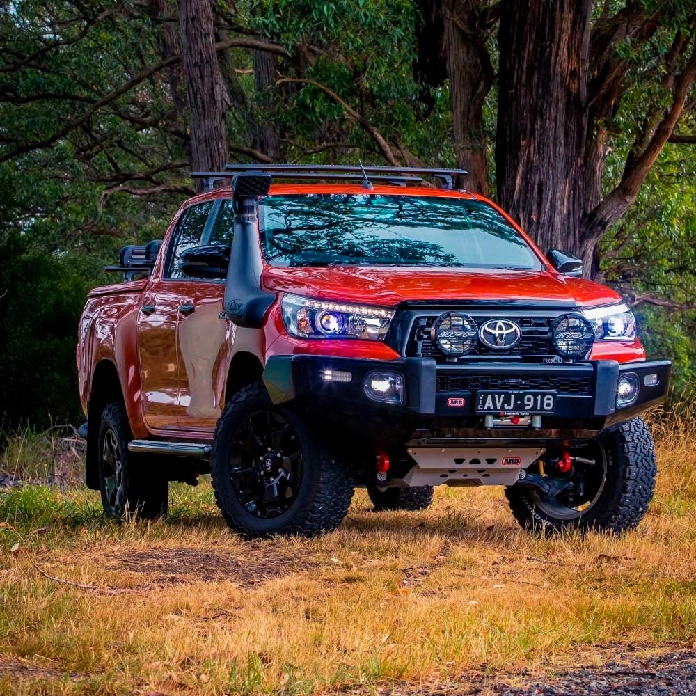 An Old Man Emu Toyota Hilux with easy installation of ARB Old Man Emu Front Coil Springs 2887, resulting in an increased ride height, parked on a dirt road.